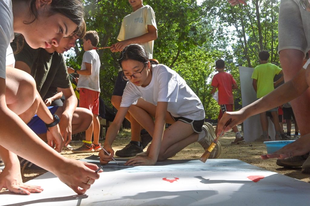 Chicos y chicas pintando un mural en el suelo durante una actividad