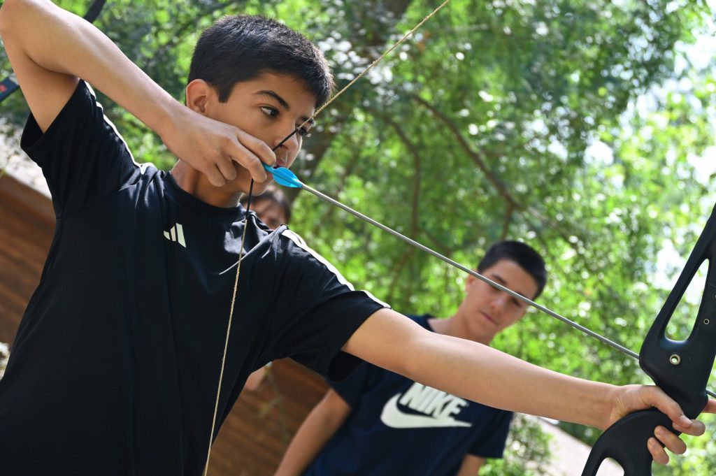 Chico practicando tiro con arco en una actividad de multiaventura